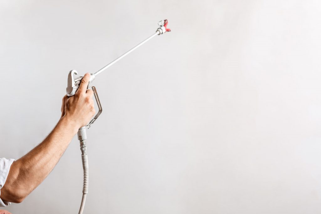 worker painting wall with spray gun white color (1)